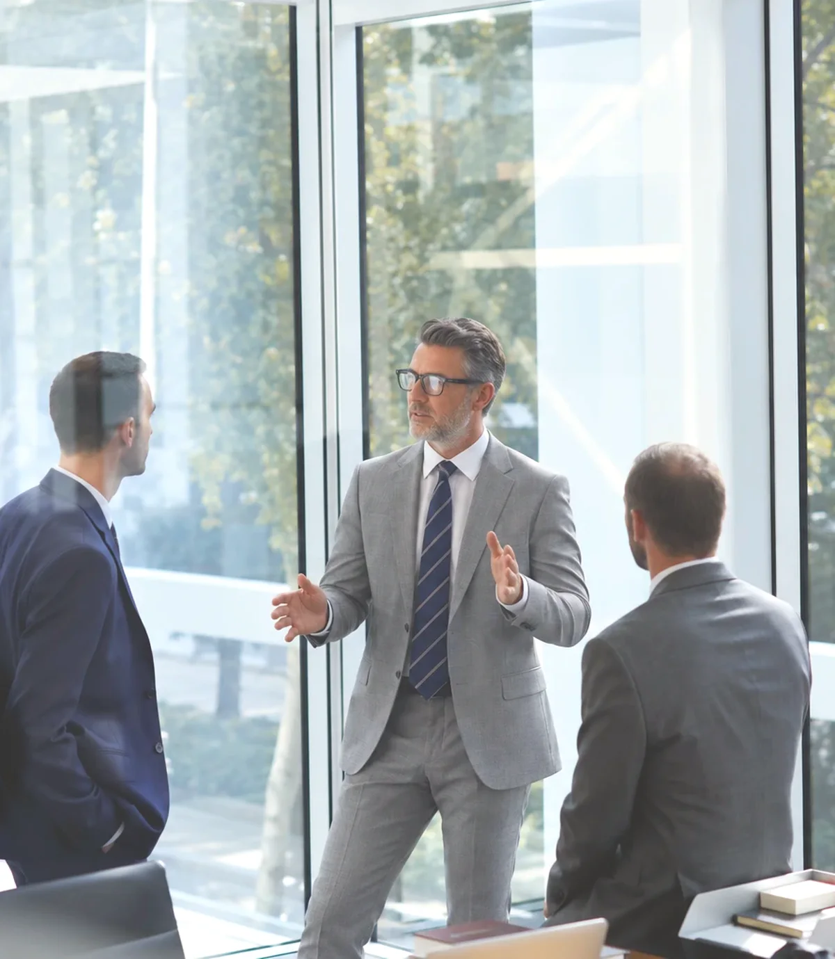 Three auditors talking beside a glass wall.